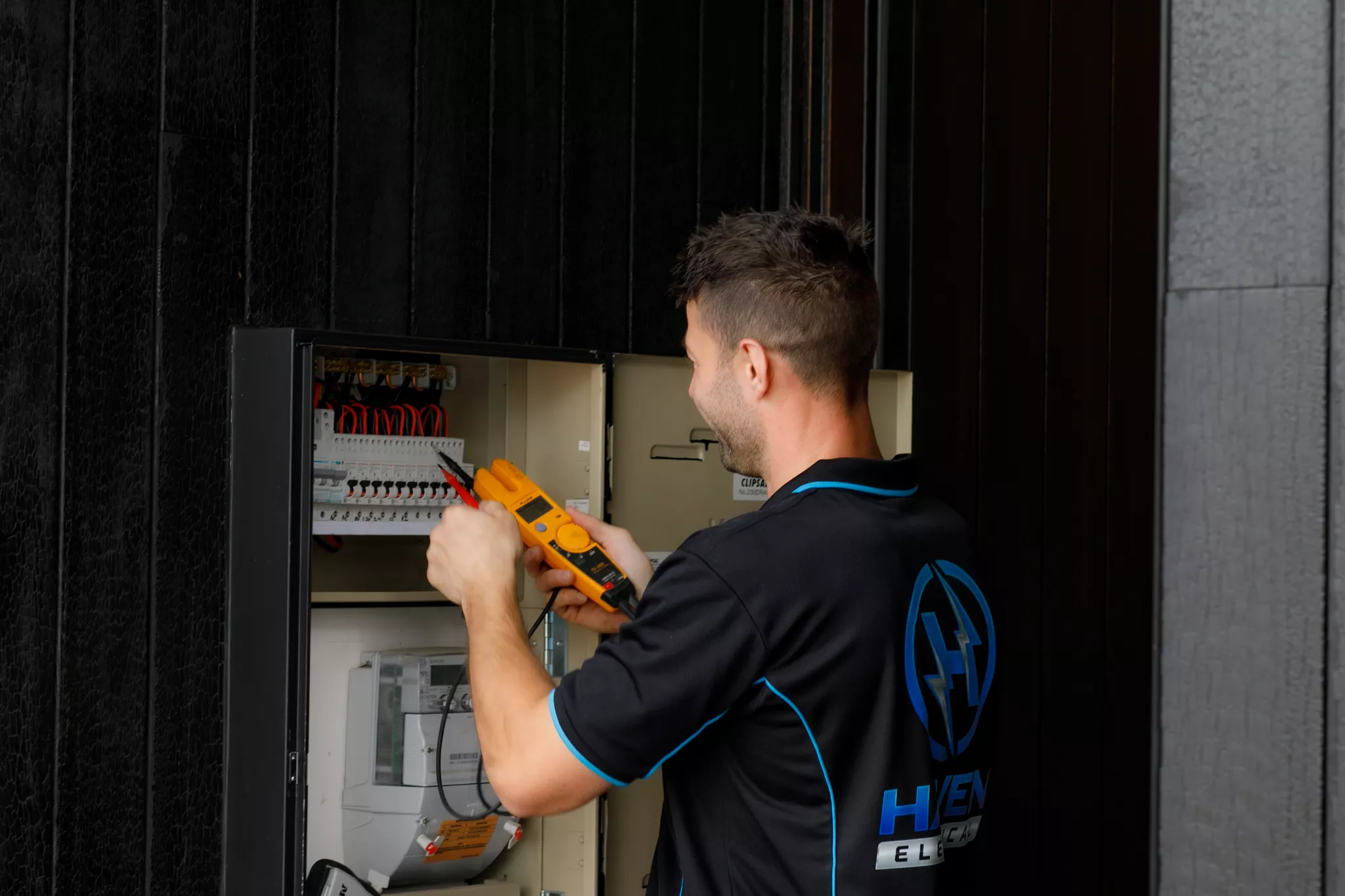 Haven Electrical technician testing switchboard with multimeter